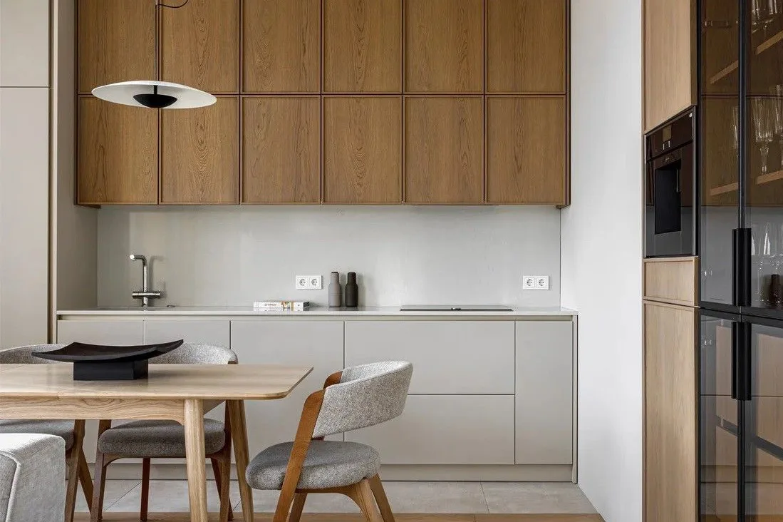 Pale kitchen cabinetry above a timber dining table
